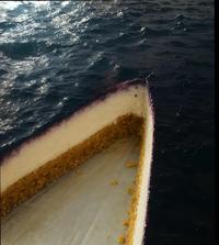 An image, possibly AI generated, of a cheesecake. The cheesecake is an optical illusion and also resembles a boat on the ocean.