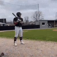 The GIF shows a man dressed in a dark blue baseball top and white pants preparing to bat before walking off the field. Tung Tung Tung Sahur, sometimes referred to as "Triple T," then walks on to the pitch. 