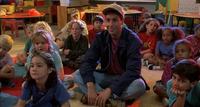 An image from the movie Billy Madison. It shows Adam Sandler as Billy Madison sitting amongst his classmates in the first grade, listening to the teacher read a story.