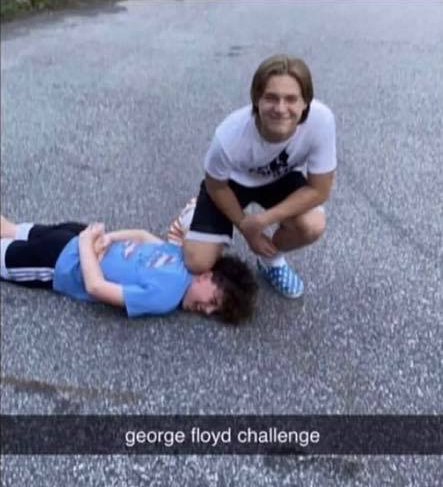 snapchat example of the George Floyd Challenge with white male with semi long parter hair with knee atop a kid with curly hair smiling on the pavement