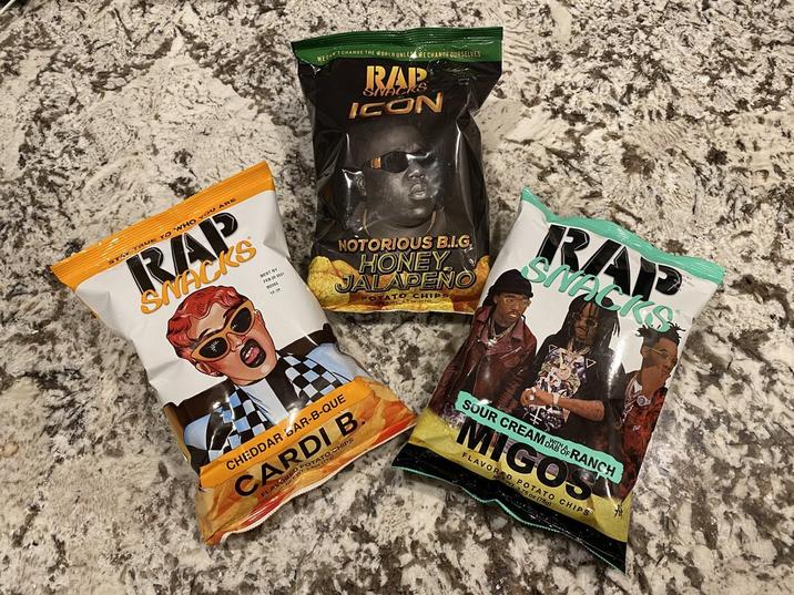 WECAN CHANGE THE WORLD UNLE WE CHANGE OURSELVES RAP SNACKS ICON STAY TRUE TO WHO YOU ARE RAP SNACKS BEST BY 0.20 2021 NOTORIOUS B.I.G HONEY JALAPENO OTATO CHIPS RAP SNACKS CHEDDAR BAR-B-QUE CARDI B. FLAV O CHIPS RWOTATO CH SOUR CREAM DAOF RANCH MIGOS FLAVORED POTATO CHIPS 2.75 oz (780)