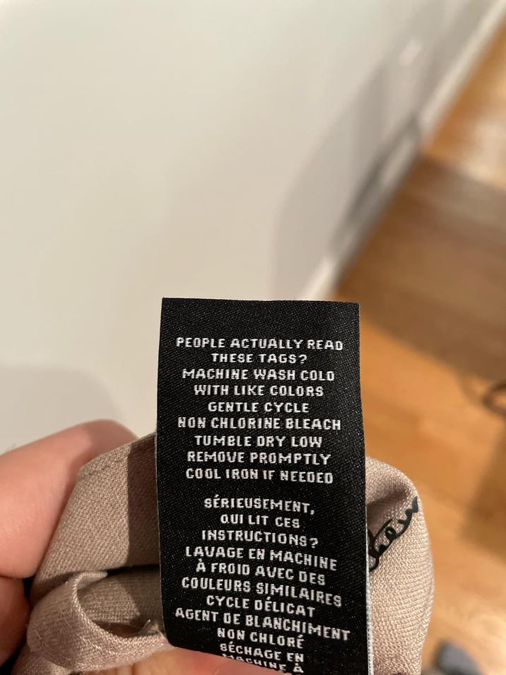 PEOPLE ACTUALLY READ THESE TAGS? MACHINE WASH COLD WITH LIKE COLORS GENTLE CYCLE NON CHLORINE BLEACH TUMBLE DRY LOW REMOVE PROMPTLY COOL IRON IF NEEDED SÉRIEUSEMENT, QUI LIT CES INSTRUCTIONS? LAVAGE EN MACHINE A FROID AVEC DES COULEURS SIMILAIRES CYCLE DÉLICAT AGENT DE BLANCHIMENT NON CHLORÉ SÉCHAGE EN MACHINE À