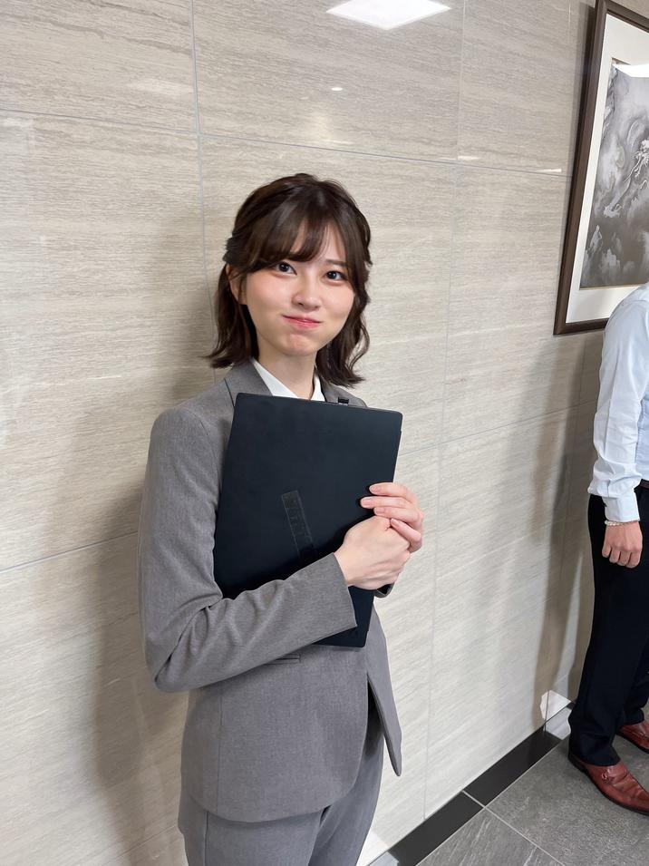 Saori Araki 'Good Morning' Salarywoman Photo The original "Japanese Salarywoman" image posted by former J-pop idol Saori Araki. The image shows the model dressed in a grey suit and holding a laptop while smiling at the camera with her cheeks puffed up.