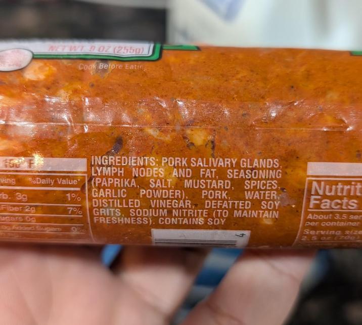 WT 9 OZ (255g) Cook Before Eatin ving rb. 3g %Daily Value* Fiber 2g ugars Og 1% 7% Og Added Sugars 0% INGREDIENTS: PORK SALIVARY GLANDS, LYMPH NODES AND FAT, SEASONING (PAPRIKA, SALT, MUSTARD, SPICES, GARLIC POWDER), PORK, WATER DISTILLED VINEGAR, DEFATTED SOY GRITS, SODIUM NITRITE (TO MAINTAIN FRESHNESS). CONTAINS SOY Nutrit Facts About 3.5 ser per container Serving size 2.5 oz (70g)