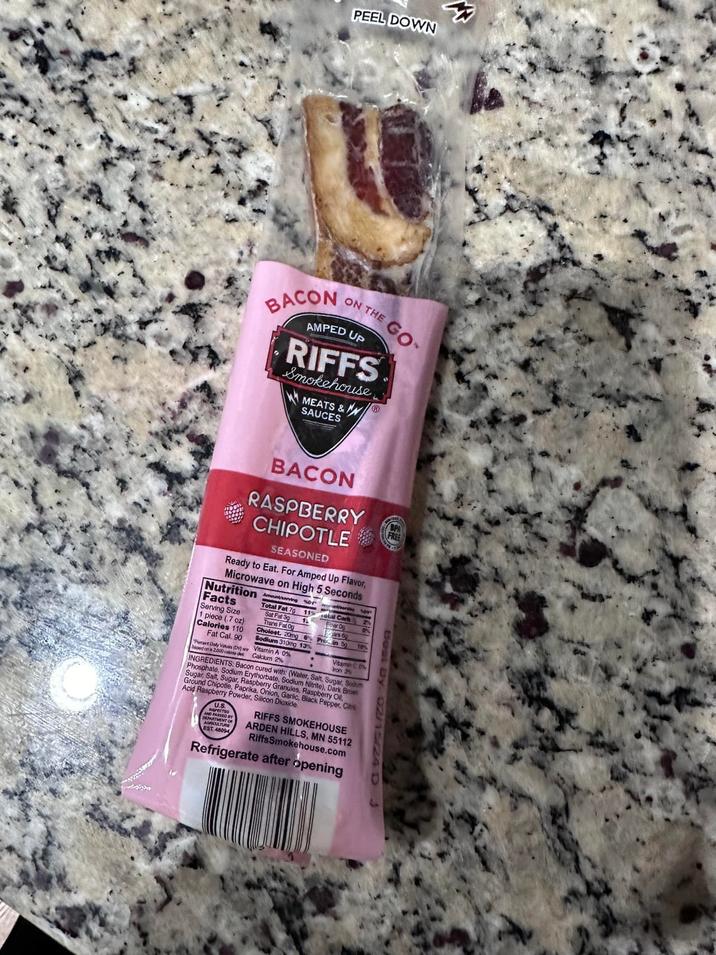PEEL DOWN BACON ON THE AMPED UP GO RIFFS Smokehouse. MEATS & SAUCES FREE BACON RASPBERRY CHIPOTLE SEASONED Ready to Eat. For Amped Up Flavor, Microwave on High 5 Seconds Nutrition Facts Serving Size Total Fat 7g 11% otal Carb Sat Fat 39 sy Best By. 15/24 D 1 piece (.7 oz) Calories 110 Fat Cal. 90 Days (D) Trans Fat Og Cholest. 20mg Sodium 310mg 13% Vitamin A 0% based on a 2,000 cale de Calcium 2% INGREDIENTS: Bacon cr 12 Proin 59 195 ars 60 Vitame C Iron 3% Phosphate, Sodium Erythorbate, Sodium Nitrite), Dark Brow Ground Sugar, Raspberry Granules, Raspberry Oil, I with: (Water, Salt, Sugar, Soum d Chipotle, Paprika, Onion, Garlic, Black Pepper, Cate Acid Raspberry Powder, Silicon Dioxide U NSPECTED DEPARTMENT AGRICULTURE AND PASSED EST. 48004 RIFFS SMOKEHOUSE ARDEN HILLS, MN 55112 RiffsSmokehouse.com Refrigerate after opening