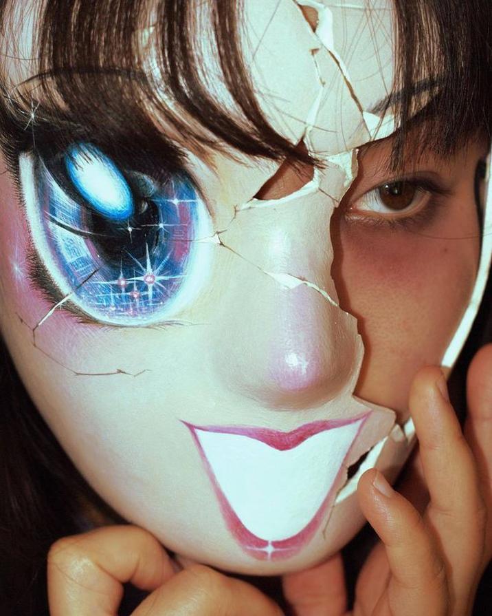 A photo of artist Dolikart in a kawaii mask. The art is based on an illustartion. 