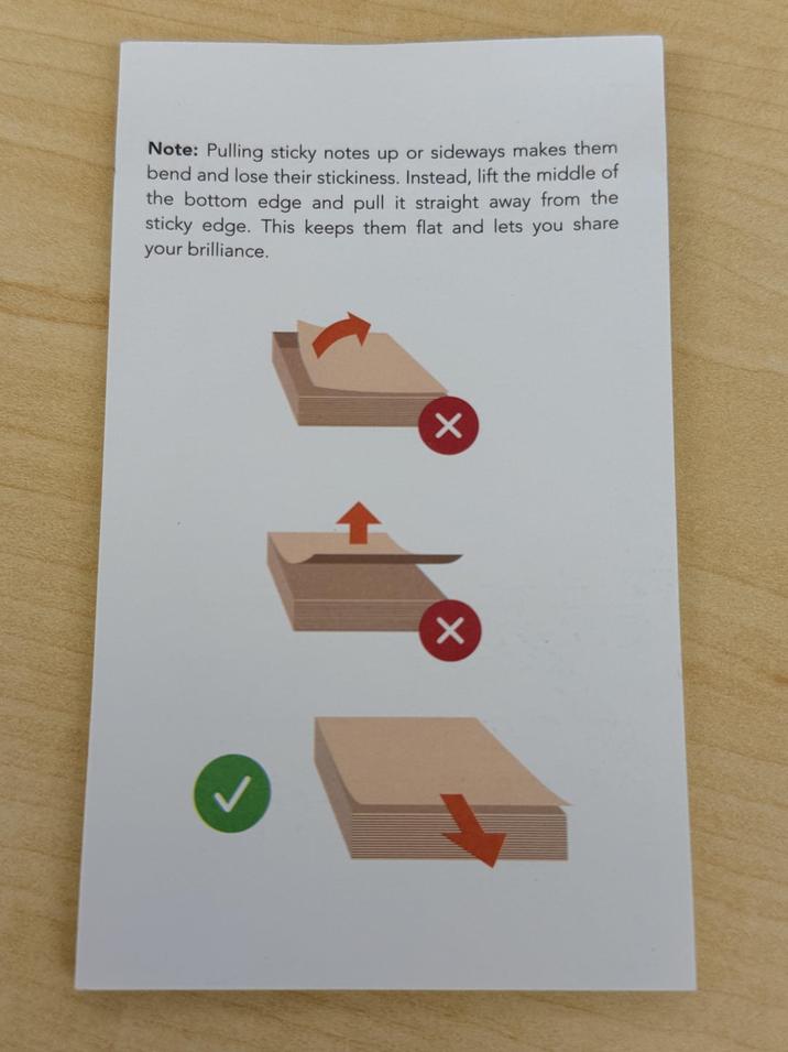 Note: Pulling sticky notes up or sideways makes them bend and lose their stickiness. Instead, lift the middle of the bottom edge and pull it straight away from the sticky edge. This keeps them flat and lets you share your brilliance. Х