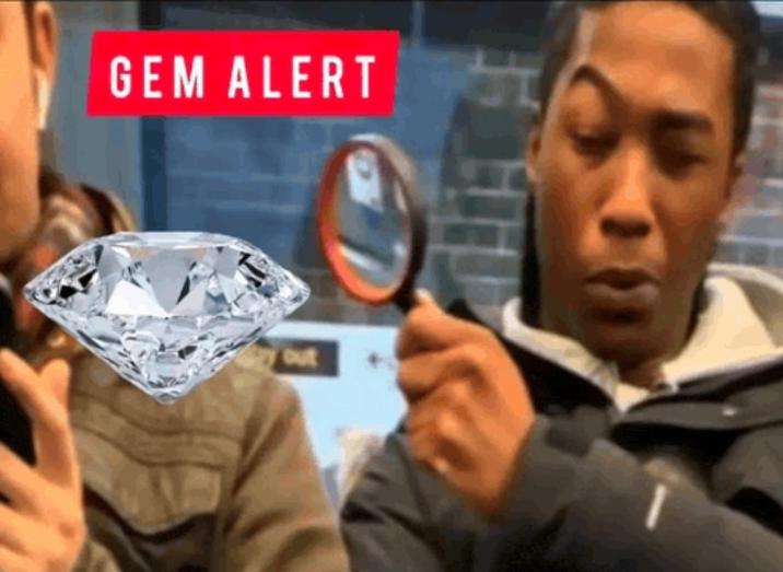A meme of a Black man looking through a magnifying glass at someone's phone. The phone is a gem and the words "gem alert" are shown.