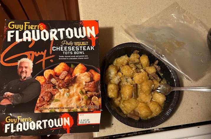 Guy Fieri's FLAUORTOWN Philly SUPER MELTY CHEESESTEAK TOTS BOWL Tender shaved steak and potato tots drenched in a decadent cheese sauce PERISHABLE KEEP FROZEN COOK THOROUGHLY NET WT. 9.50Z (2699) Guy Fieri's FLAUORTOWN BEST BY 20 2827 6281 012026 EST 24