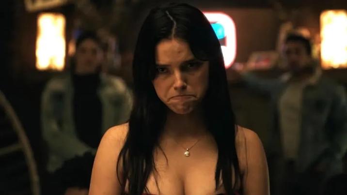 An image of Nikki from the 2026 horror movie "Obsession" frowning or pouting. She is sitting at a dinner table in a restaurant.