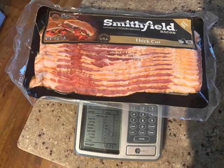 KEEP REFRIGERATED S ONCE OPENED USE WITHIN 7 Ders Serving Suppation NET WT 16 02 (1LB) FORK Smithfield NATURALLY HICKORY SMOKED RAISED USA Thick Cut BACON IN THE C0000 ES779C 13 LA2 11:02 USE BY NOV 11 2026 INSP BY93446387 LOT619553 Calories 2000 Daily Cal Total Fat Sat Fat 59 Cholest ing Sodium Total Carb 0000 7 8 SAVE 0 CLEAR SET G/OZ TARE D. Fiber Sugars Protein Weight 0 12.35 TOTAL ITRICS EASY PEEL Ib