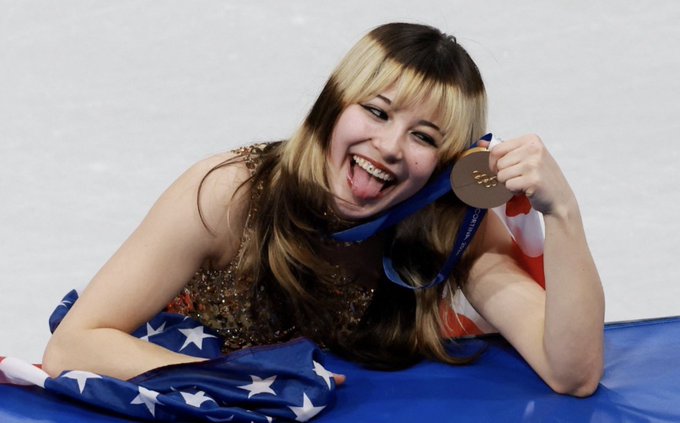 A photo of Alysa Liu. She has her tongue out, holding her medal.