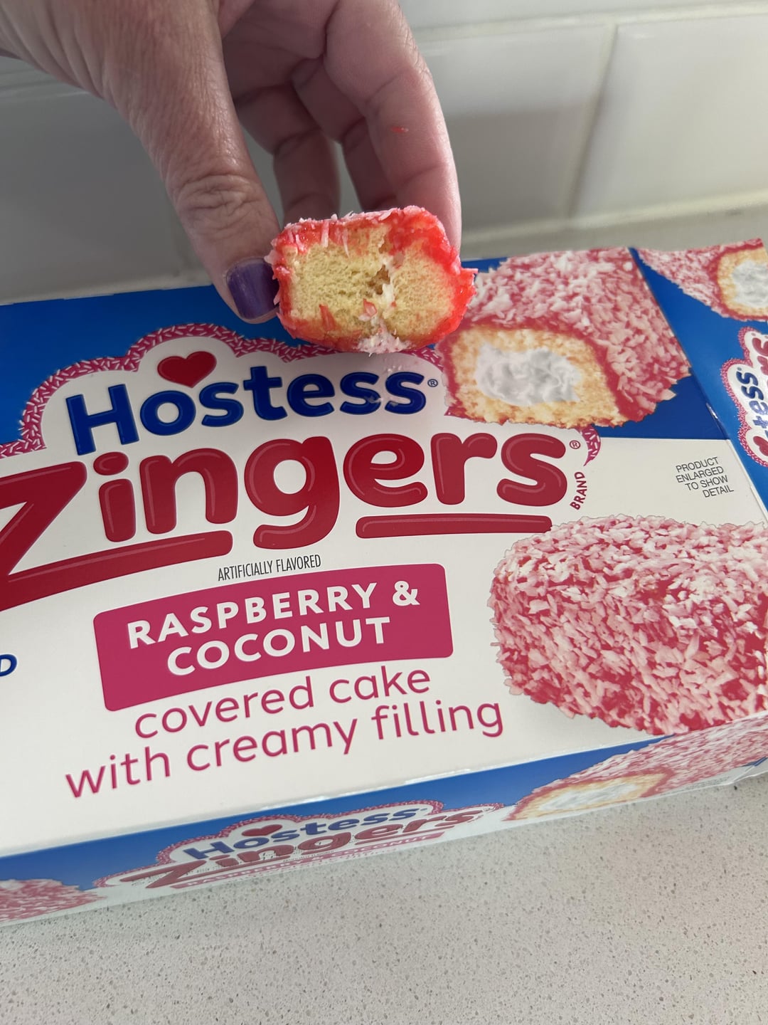 D Hostess Zingers ARTIFICIALLY FLAVORED RASPBERRY & COCONUT covered cake with creamy filling Hostess PRODUCT ENLARGED TO SHOW DETAIL ess